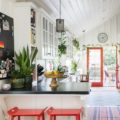 summer farmhouse-style kitchen with red stools and red door
